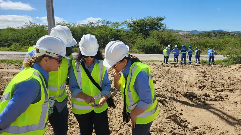 Equipe de capacete e colete refletivo conferindo o local da obra