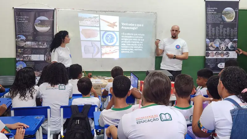 Estudantes assistindo a uma apresentação sobre arqueologia em sala de aula