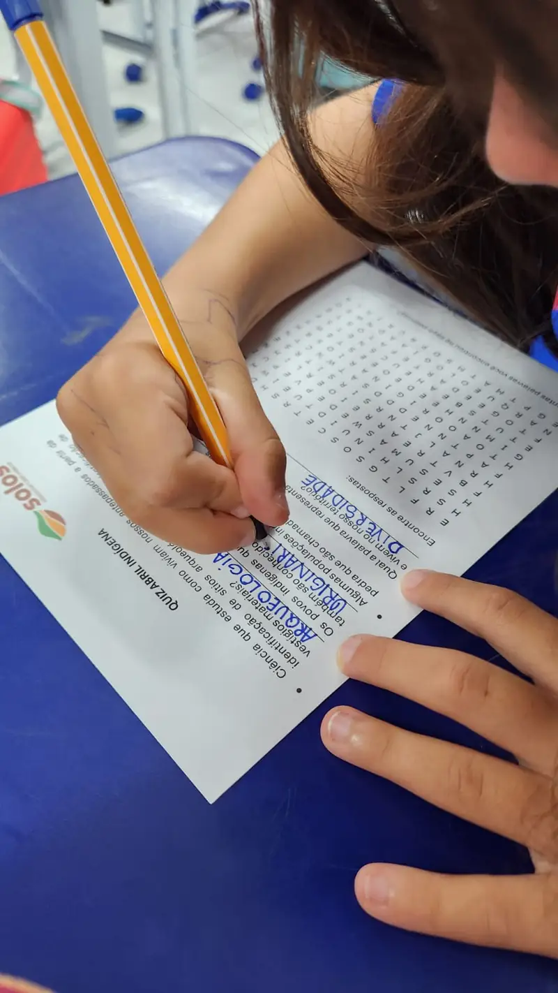 Estudante escrevendo em uma atividade impressa de educação patrimonial