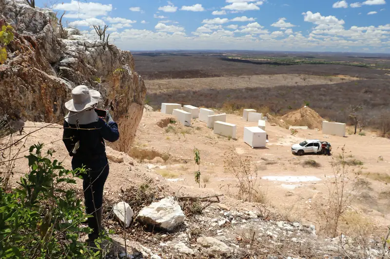 Área de mineração de rochas ornamentais, com blocos de pedra e pesquisadora observando a paisagem