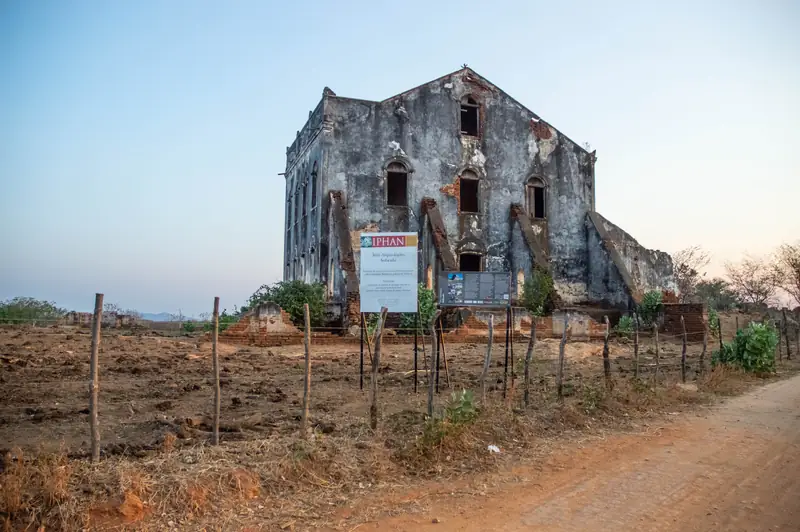 Edificação histórica em ruínas, com placa informativa, ao entardecer