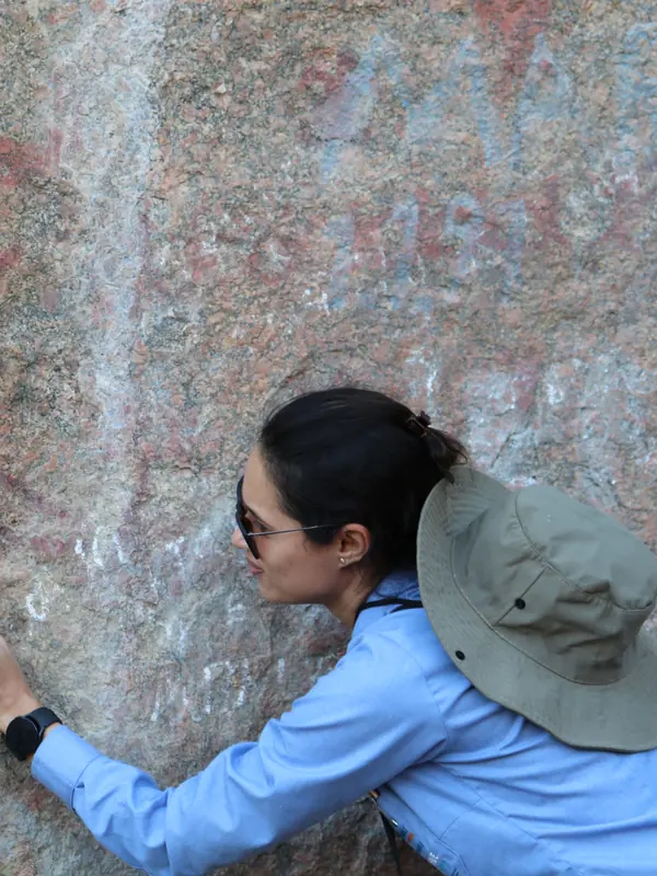 Rúbia Nogueira fotografando uma parede rochosa com pinturas