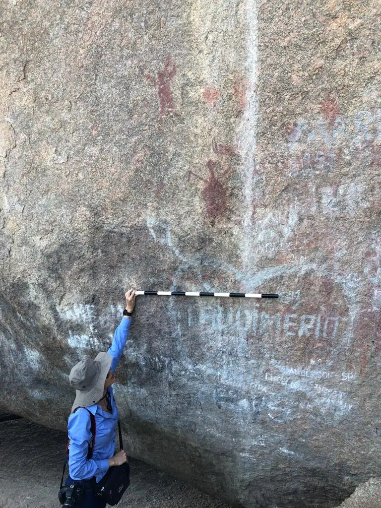 Pesquisadora registrando um paredão rochoso com escala